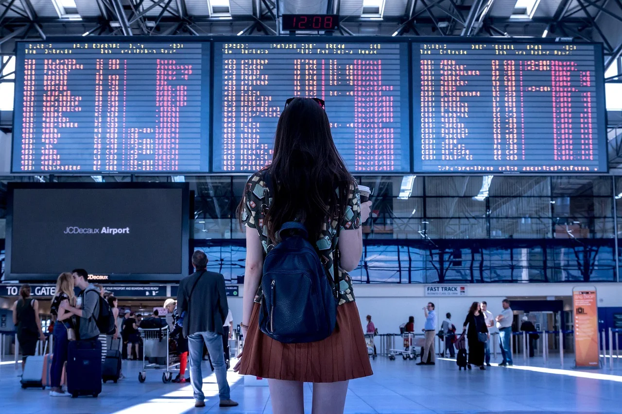 Podróżni na lotnisku JCDdeux Airport, tablica odlotów i osoba z plecakiem, praktyczne wskazówki Wizz Air