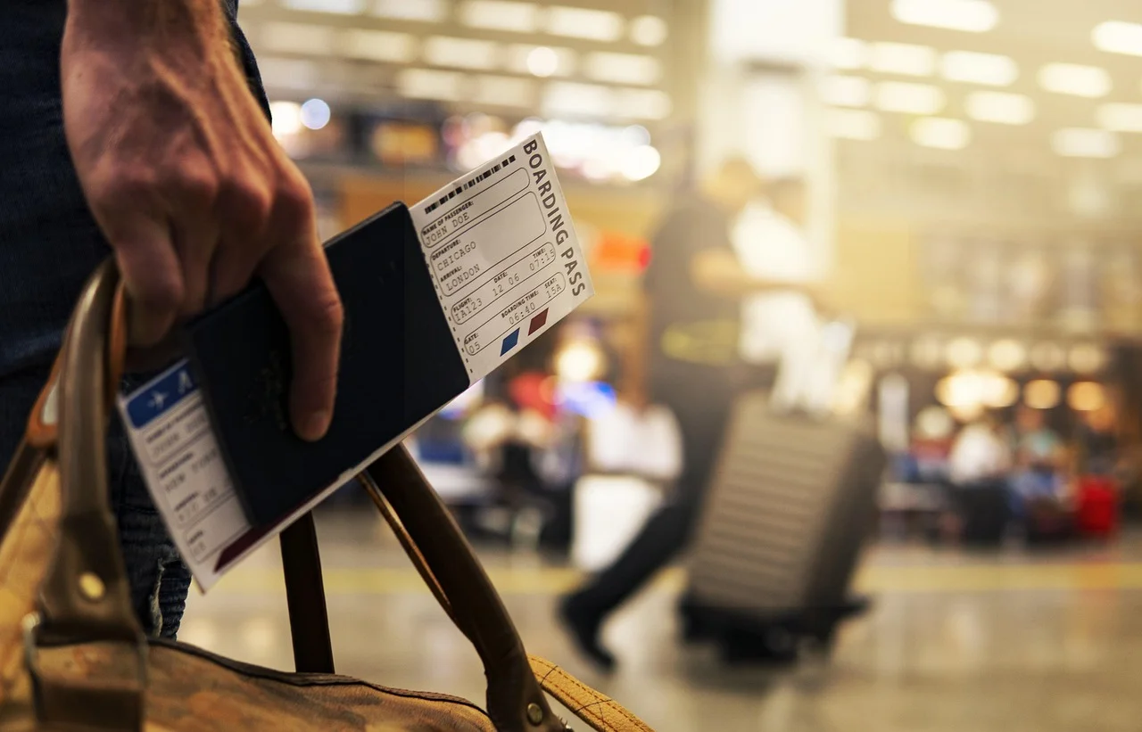 Bilet boarding pass w ręku przy walizce w podróży lotniczej, praktyczne limity bagażu podręcznego