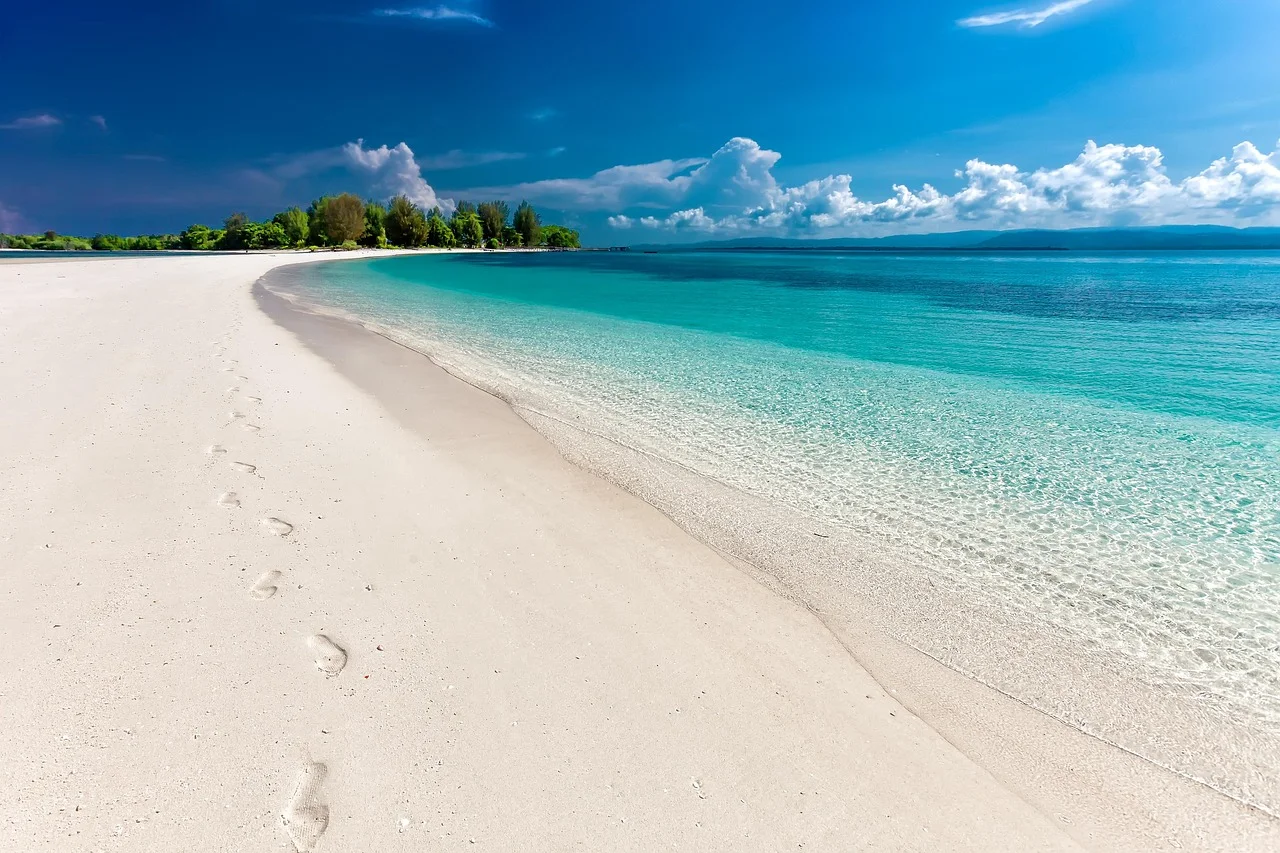 Biała piaszczysta plaża Zanzibaru z turkusową wodą i spokojnym niebem, idealna na bezstresowy wypoczynek