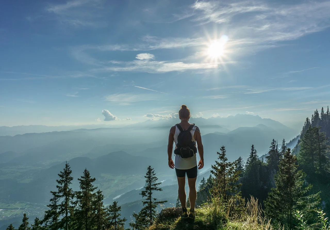 Wędrowiec na szlaku w górach, złote światło nad doliną; inspiracja do planowania wyjścia bez stresu